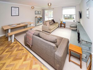 A living room with a sofa, a wooden table, a bench, a bookshelf, and a TV.