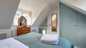 Ein Schlafzimmer mit Bett, Kommode und Spiegel.