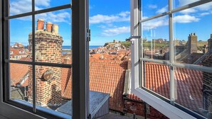 Blick aus einem Fenster auf eine Stadtansicht mit roten Ziegeldächern und historischen Gebäuden.