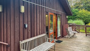 Eine Holzhütte mit einer Terrasse, einer Bank und zwei Stühlen.