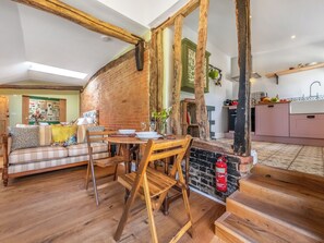 A cozy living room with a wooden dining table, a sofa, and a fireplace. - The Old Press - UK50806 (Cratfield, near Laxfield)