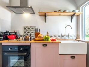 A modern kitchen with a built-in oven, a red kettle, a bread loaf, and a variety of kitchen utensils on the counter. - The Old Press - UK50806 (Cratfield, near Laxfield)