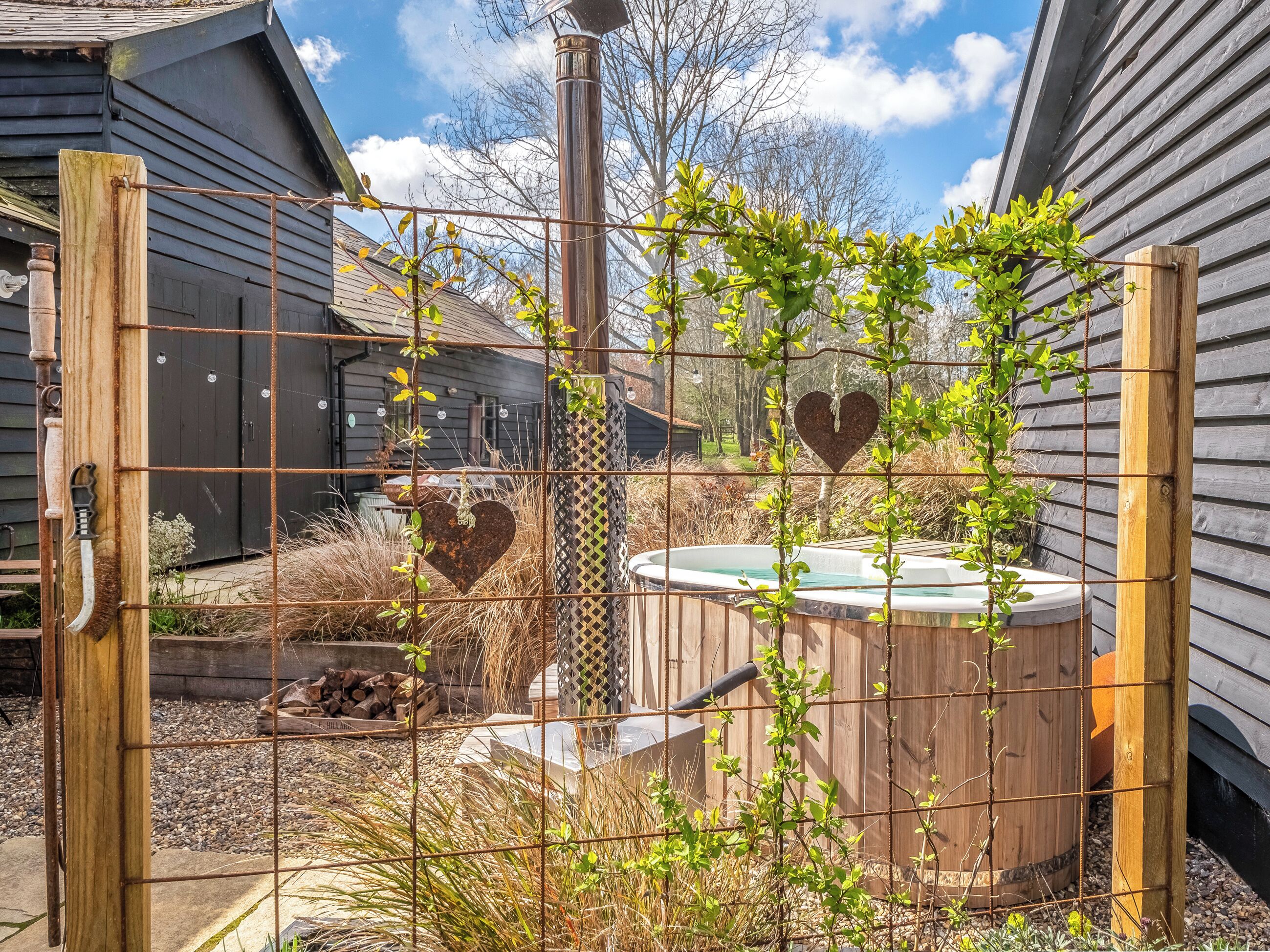 A rustic outdoor area with a wooden fence, a hot tub, and a heart-shaped decoration.