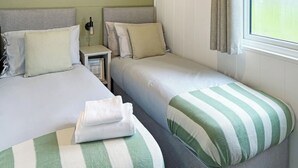 A twin room with two beds, a nightstand, and a window with curtains.
