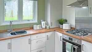 A modern kitchen with a stainless steel range hood, a built-in oven, and a window with a view of greenery.