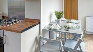 A modern kitchen with a wooden countertop, a gas stove, and a dining area with a table set for two.