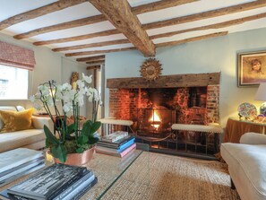 A cozy living room with exposed wooden beams, a brick fireplace, and a comfortable seating area.