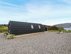 A modern, single-story building with a sloped roof, a small window, and a wooden deck.
