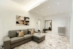 Ein modernes Wohnzimmer mit einem Ecksofa, einem großen abstrakten Gemälde, einem Spiegel und einem Boden mit Steinmuster.
