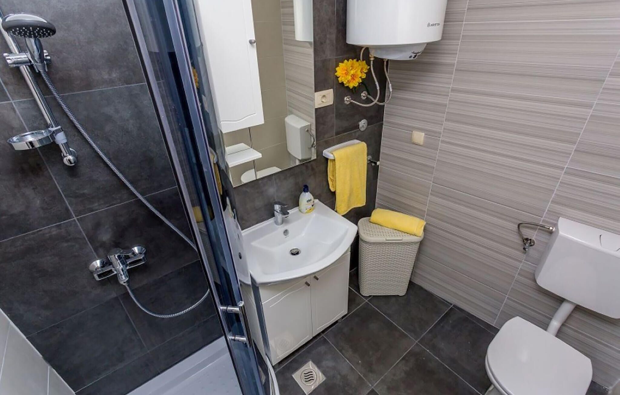 A modern bathroom with a glass shower enclosure, a white sink, and a toilet.