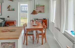 A dining area with a wooden table and chairs, a vase with flowers, and a hanging lamp. - Lovely home in Thyborøn with WiFi (Thyborøn)