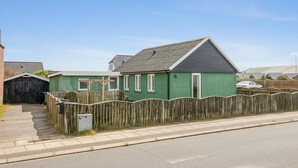 Een woonhuis met een tuinhuis, een houten hek en een garage.