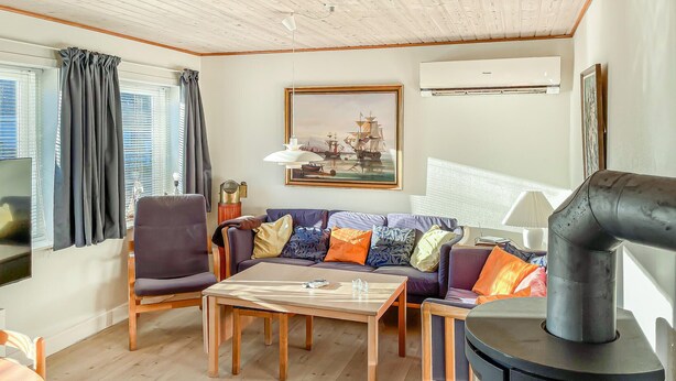 Una sala de estar acogedora con un sofá, sillones, una mesa y un estufa de leña.