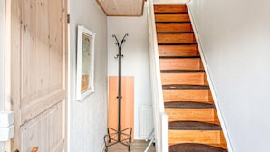 Una escalera de madera con una pared blanca y un radiador en el rellano.