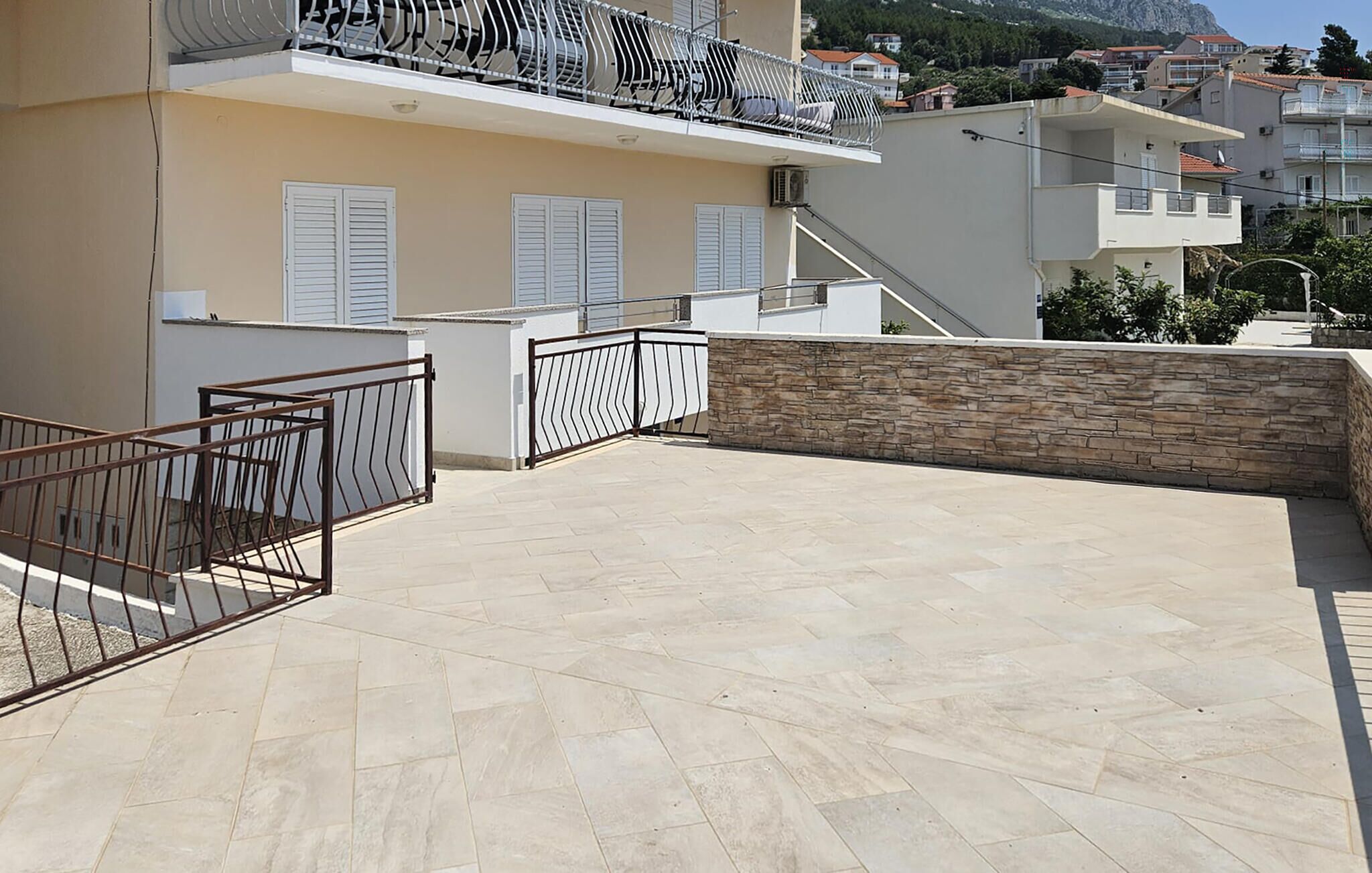 A rooftop terrace with a stone wall and metal railing.