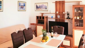 Un coin repas avec une table dressée pour deux personnes, un buffet en bois doté de portes en verre et une cheminée.
