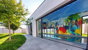 A modern building with large windows and a colorful mural on the exterior wall. - Villa piscine intérieure (Royan)