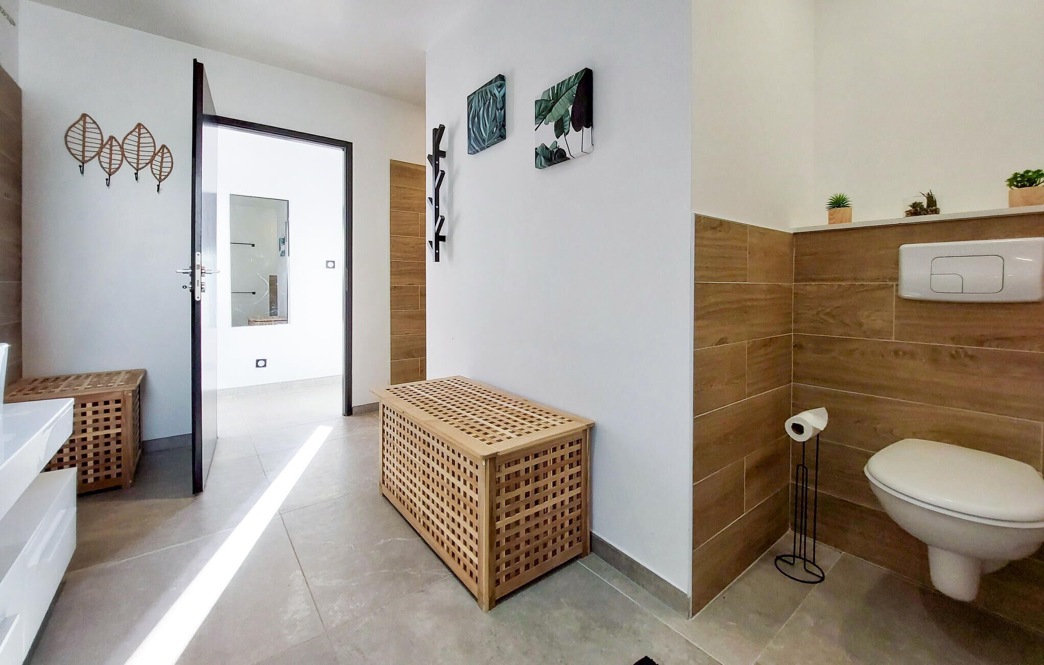 Un baño moderno con inodoro, lavamanos y una cesta de madera para la ropa.