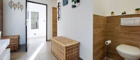 Un baño moderno con inodoro, lavamanos y una cesta de madera para la ropa.