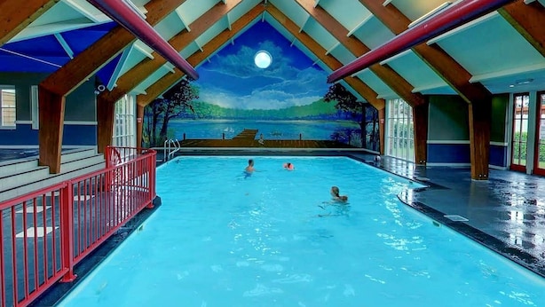 An indoor swimming pool with a mural of a night sky and landscape on the ceiling, wooden beams, and a red safety railing. - Beautiful home in Voorthuizen (Voorthuizen)