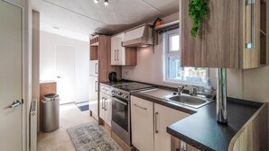 A modern kitchen with a stove, sink, and wooden cabinets. - Beautiful home in Voorthuizen (Voorthuizen)