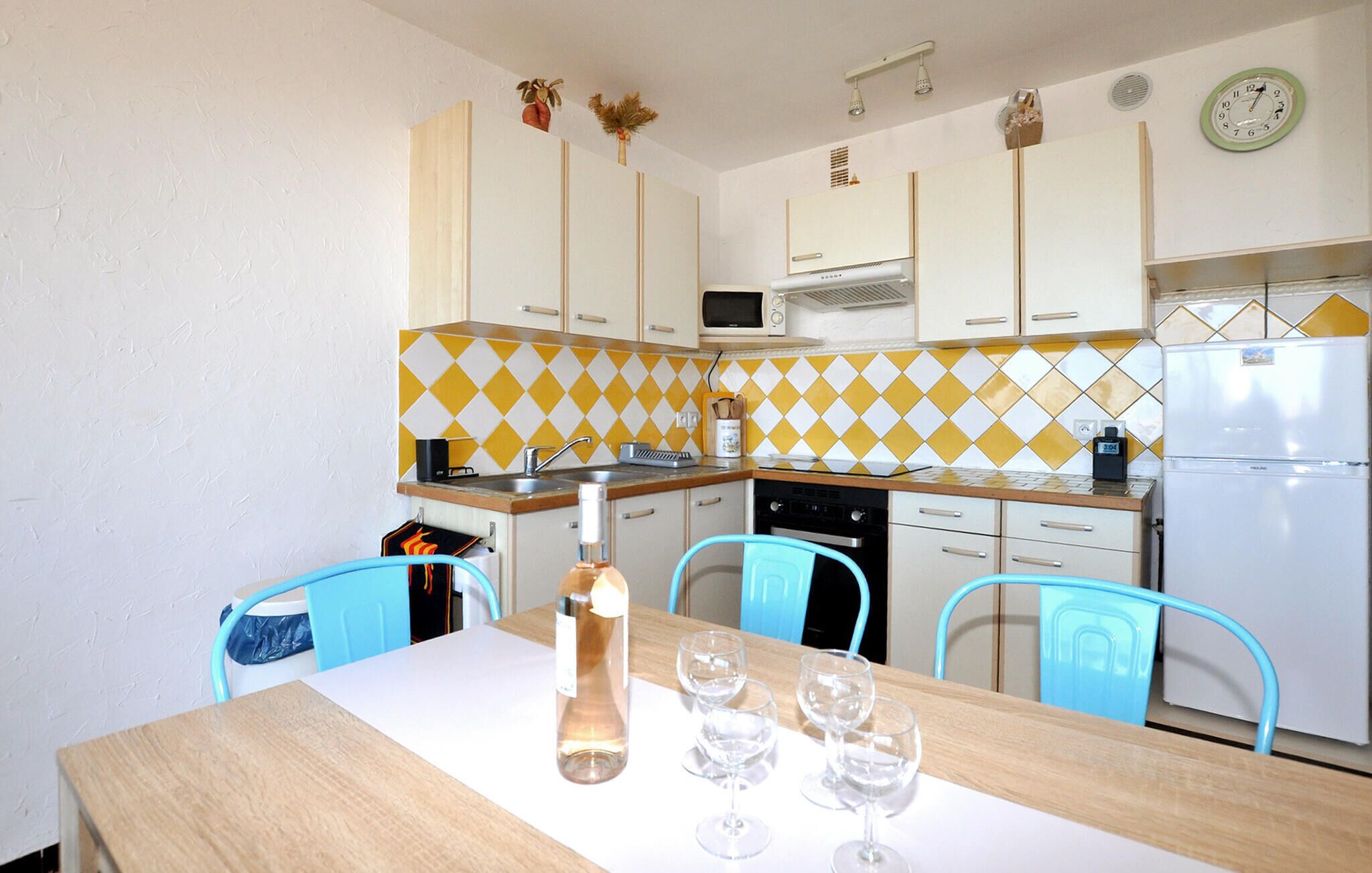 A kitchen with a wooden table, four chairs, a sink, a microwave, a stove, and a refrigerator.