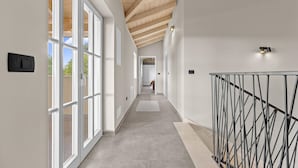 Een moderne hal met grote ramen, een houten plafond en een metalen balustrade.