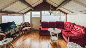 A cozy room with a red sofa, a small round table, and a TV on a wooden stand. - Lake front home in Leksand with lake view (Leksand)