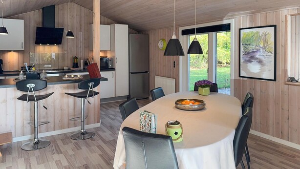 Una cucina moderna con mobili in legno, un'area pranzo con tavolo bianco e vista all'esterno.