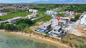 An aerial view of a coastal residential area with modern buildings, a beach, and mountains in the background. - Nice apartment in Privlaka with WiFi (Privlaka)