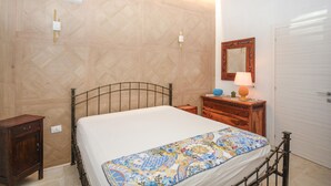 Une chambre à coucher comprenant un lit, une commode en bois, une table de chevet, un miroir et un appareil de climatisation.