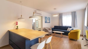 Moderni olohuone, jossa on puinen ruokapöytä, sohva ja keltainen nojatuoli.