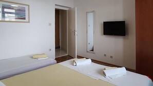 Een hotelkamer met twee bedden, een televisie en een deur naar een badkamer.