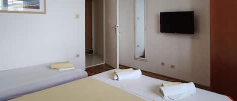 Een hotelkamer met twee bedden, een televisie en een deur naar een badkamer.
