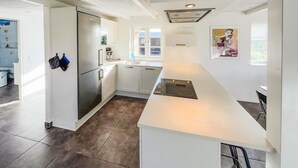 Une cuisine moderne avec des armoires blanches, un réfrigérateur en acier inoxydable et un grand îlot central.