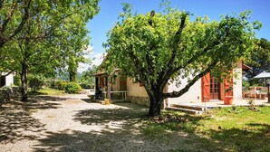Un edificio rustico con un vialetto sterrato che conduce a un’area salotto esterna coperta.