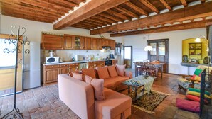 Una sala de estar acogedora con un sofá, una mesa de comedor y una zona de cocina con armarios de madera y un refrigerador.