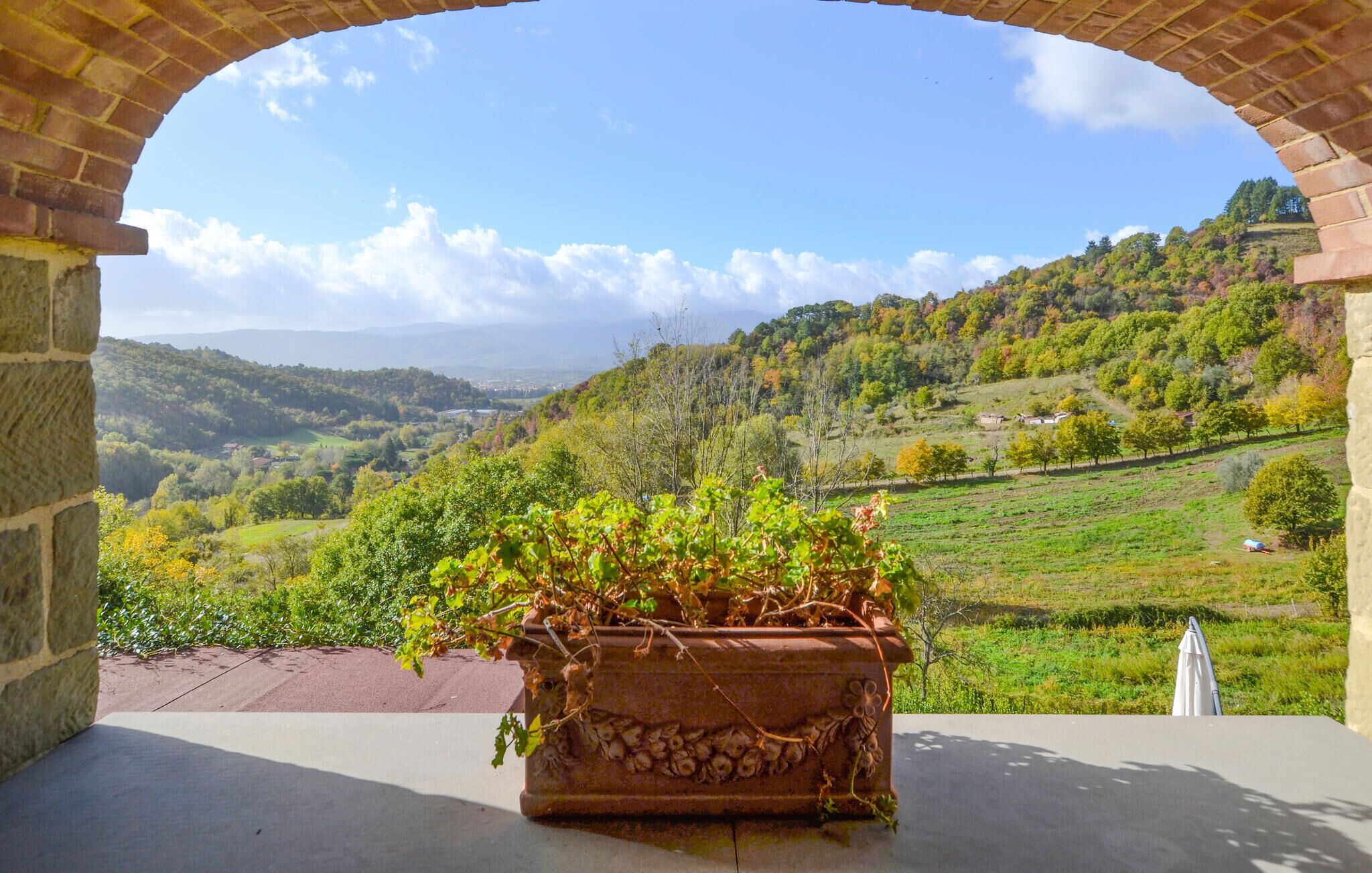 Un arc de pedra amb vista a una vall exuberanta, i al capdamunt, les siluetes de les colines llunyanes sota un cel serè.