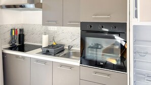 Una cocina moderna con horno empotrado, campana extractora de acero inoxidable y salpicadero de mármol.