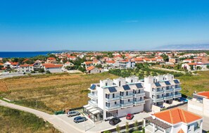 A modern apartment complex with multiple balconies, a parking area, and a view of the sea. - Amazing home in Privlaka with sauna (Privlaka)