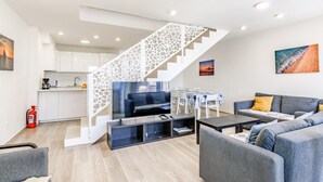 A modern living room with a flat-screen TV, grey sofas, a coffee table, and a staircase with a white railing. - Amazing home in Privlaka with sauna (Privlaka)