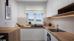 Une cuisine moderne avec vue sur la plage, dotée de plans de travail en bois et de meubles de rangement blancs.