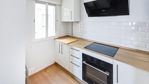 A modern kitchen with white cabinets, a black stove, and a window. - Amazing apartment in Barbate with WiFi (Barbate)