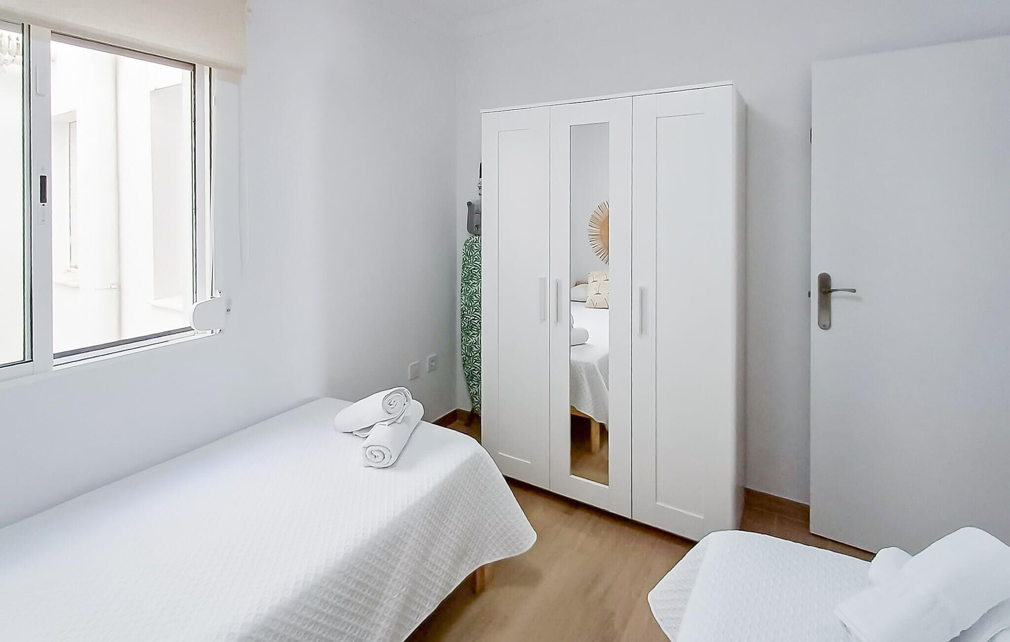 Ein kleines, sauberes Zimmer mit einem Einzelbett, einem Kleiderschrank und einem Fenster.