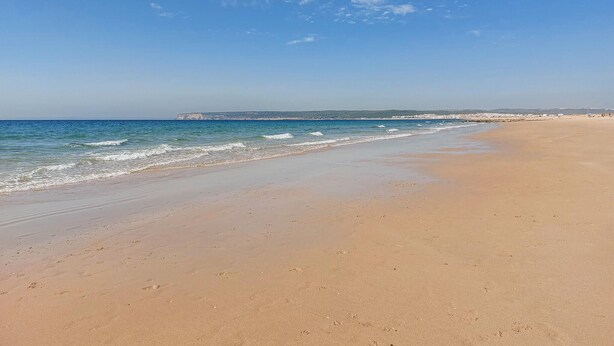A wide sandy beach with gentle waves, a clear sky, and a distant rocky coastline. - Amazing apartment in Barbate with WiFi (Barbate)