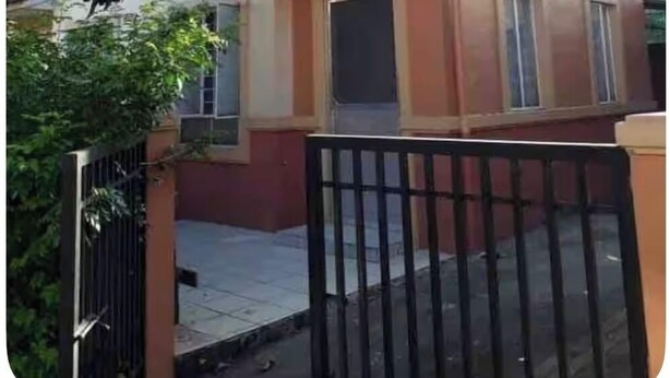 Une maison à deux étages, dotée d’une entrée fermée par un portail, d’un petit porche et d’une fenêtre bien visible.