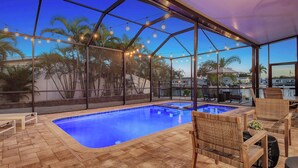 A covered swimming pool area with a clear view of palm trees and a poolside seating area. - No Bad Days - Boat Dock, Heated Pool & Hot tub, Beach Gear, 5 Mins to AMI (Bradenton)