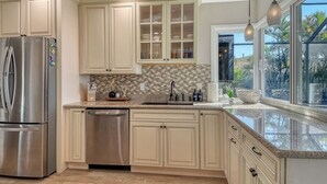 A modern kitchen with a stainless steel refrigerator, dishwasher, and granite countertops. - No Bad Days - Boat Dock, Heated Pool & Hot tub, Beach Gear, 5 Mins to AMI (Bradenton)