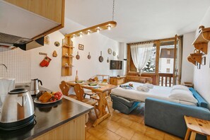 A compact hotel room with a kitchenette, a dining area, a bed, and a view of the outside. - Studio Valleverde 11D Ski In Ski Out (Sestriere)