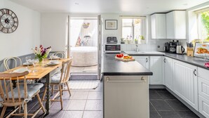Une cuisine moderne avec des meubles blancs, une table à manger en bois et un plan de travail noir.